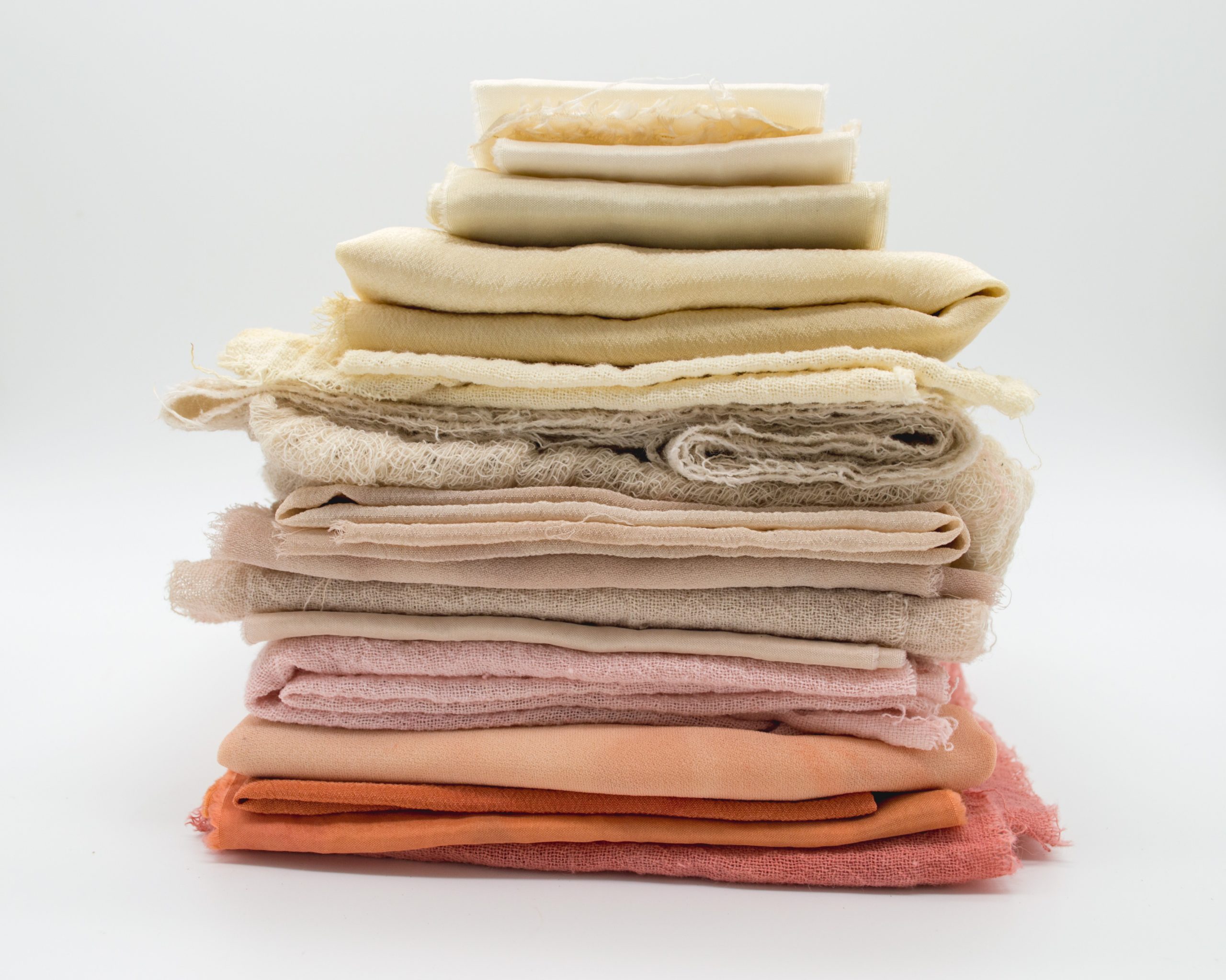 A photo of different coloured fabric scraps folded and piled up in a colour gradient