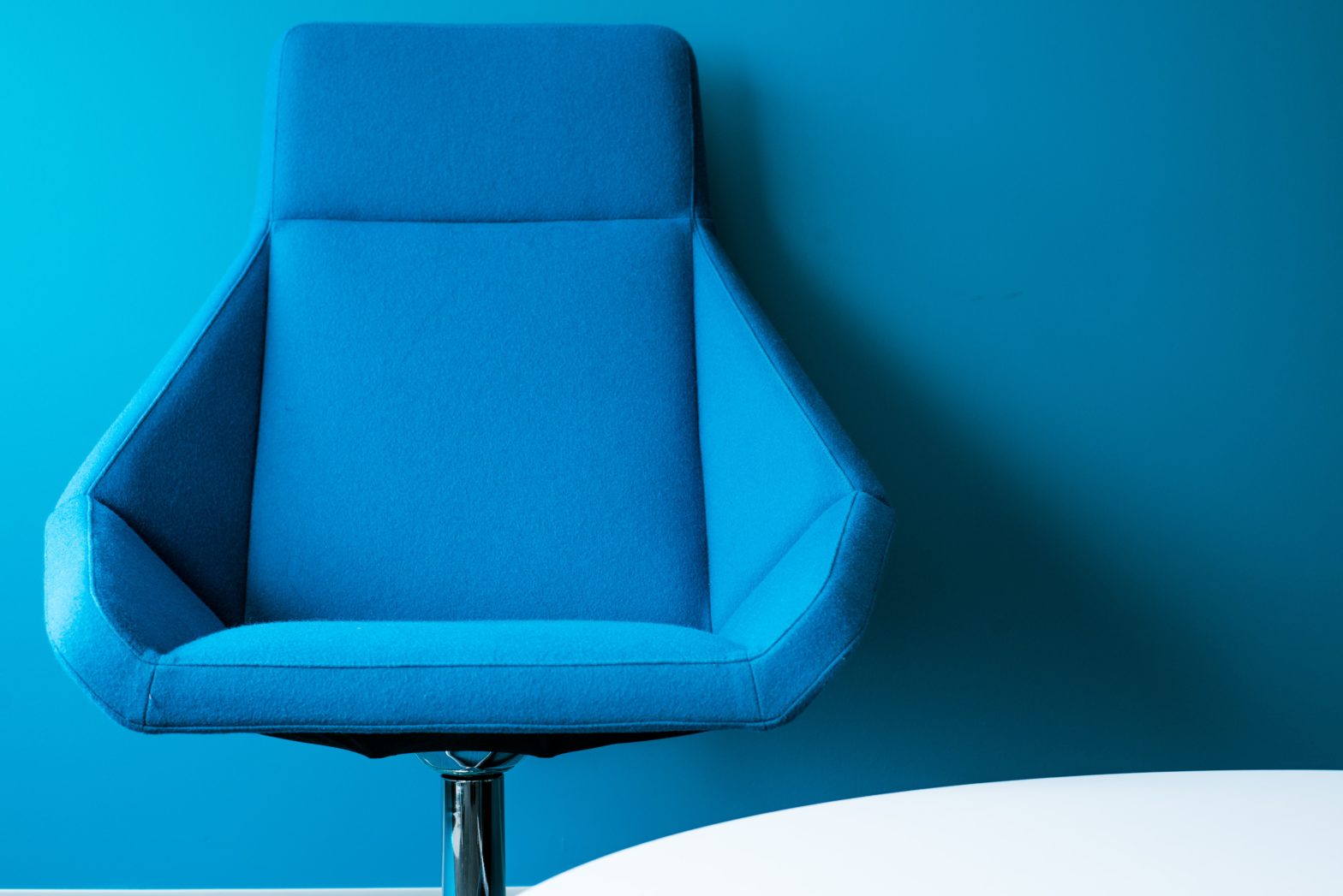 A stylized photo of a blue office chair against a blue wall