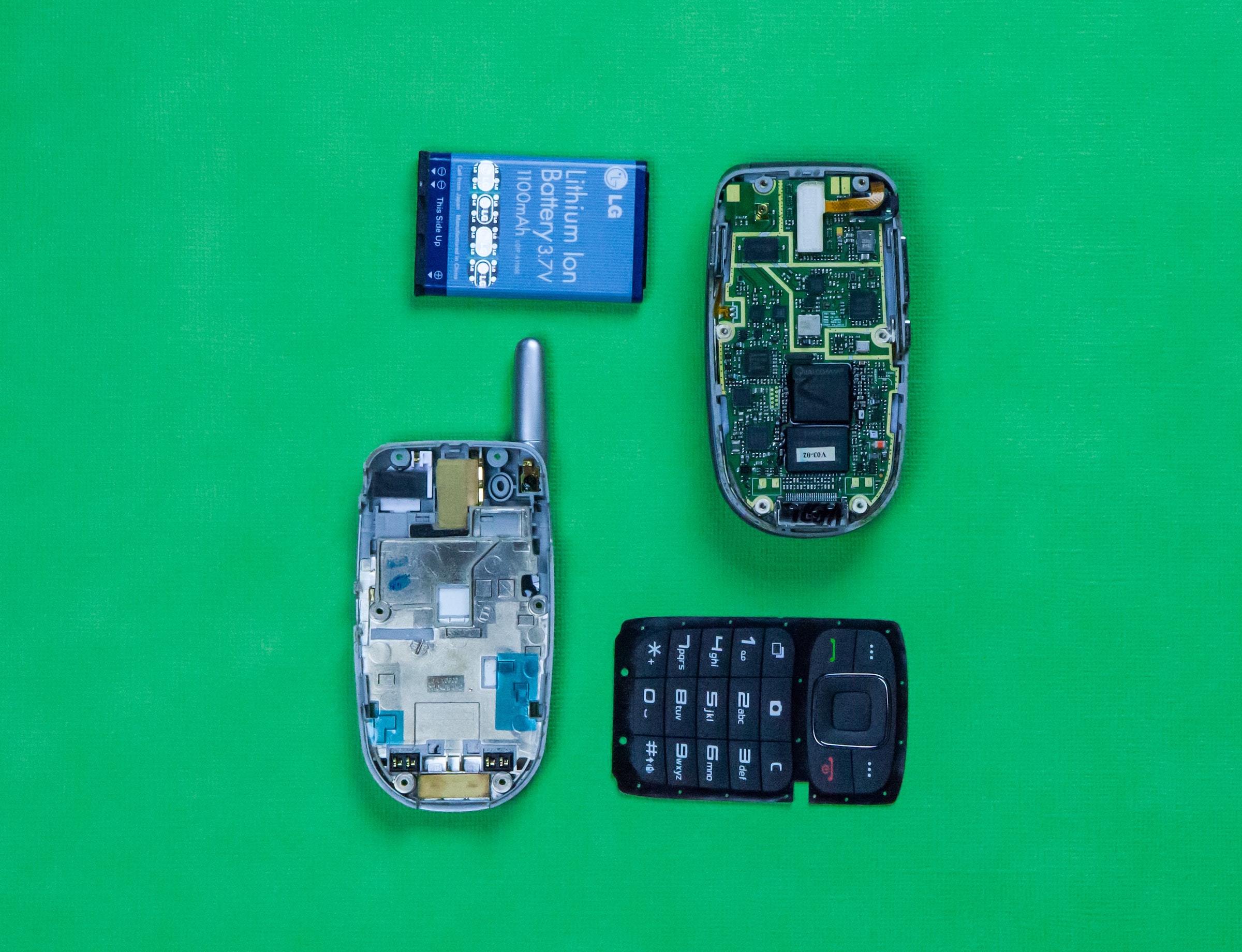 A top down photo of old cell phone parts on a green background