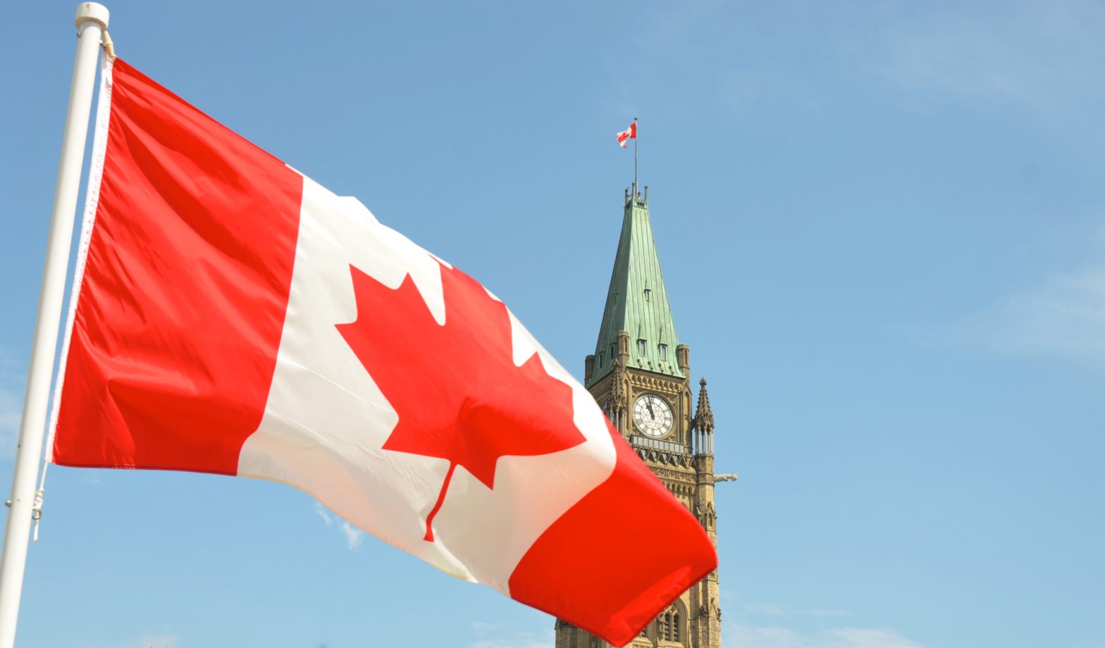 A photo of the Canadian flag in front of the Canadian parliament building