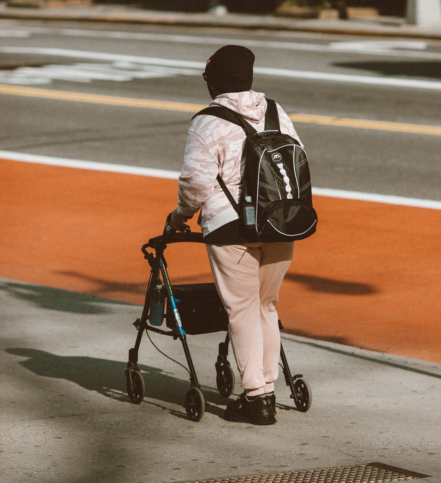 A young person using their walker (assistive technology) on a city sidewalk
