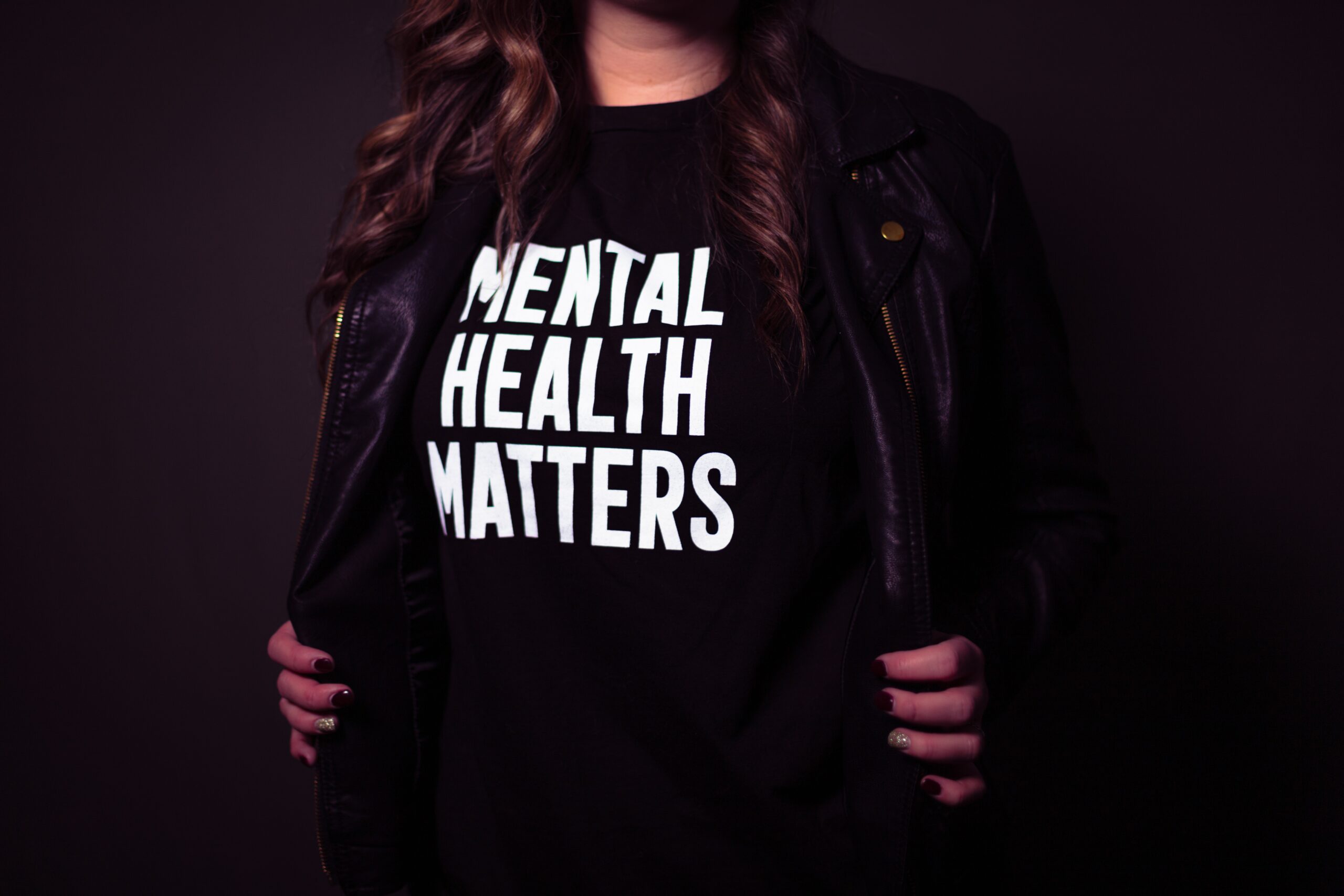 A photo of a woman revealing a Tshirt that reads Mental Health Matters