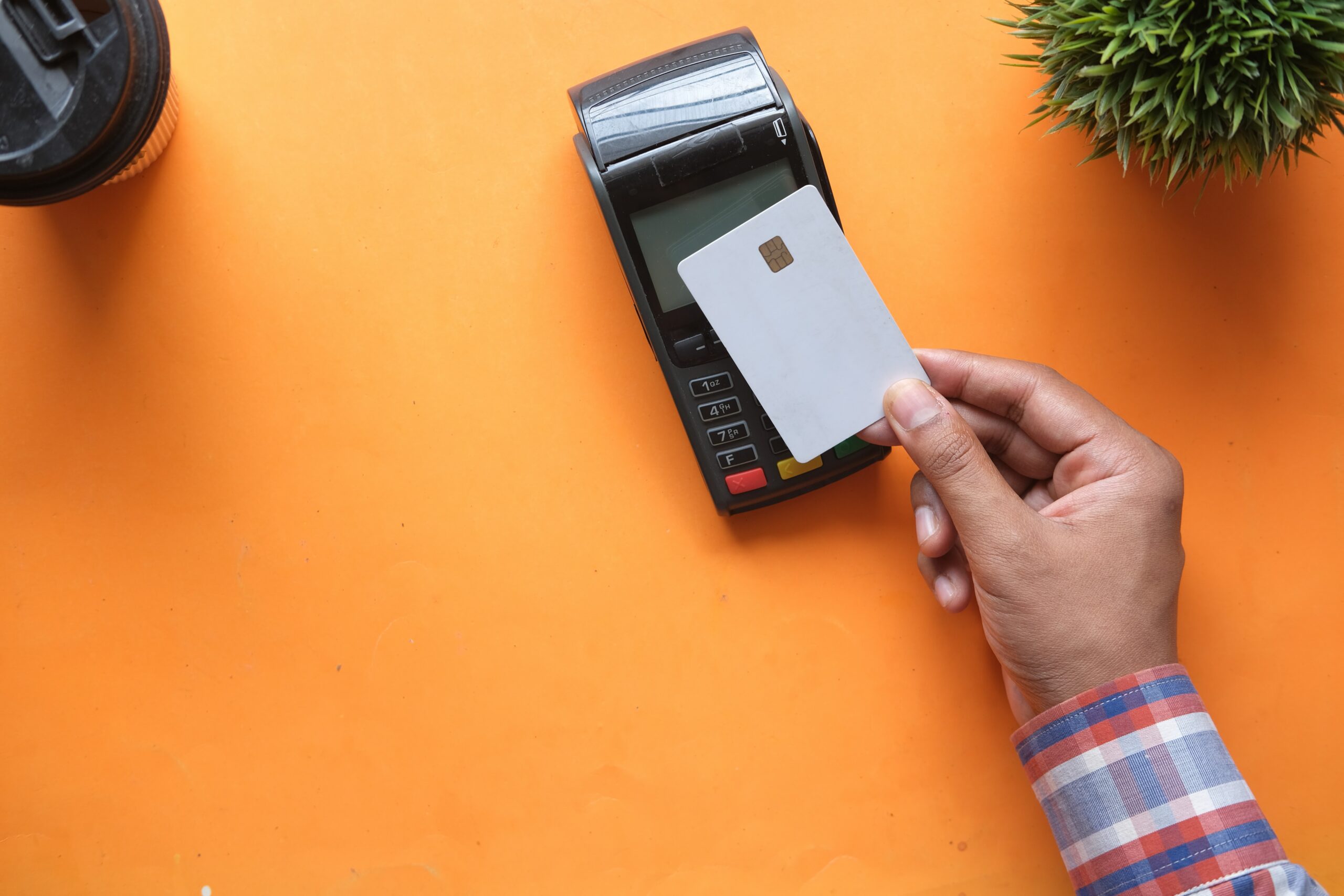 A photo of a user tapping an unbranded bank card on a portable payment machine, indicating they are making a purchase
