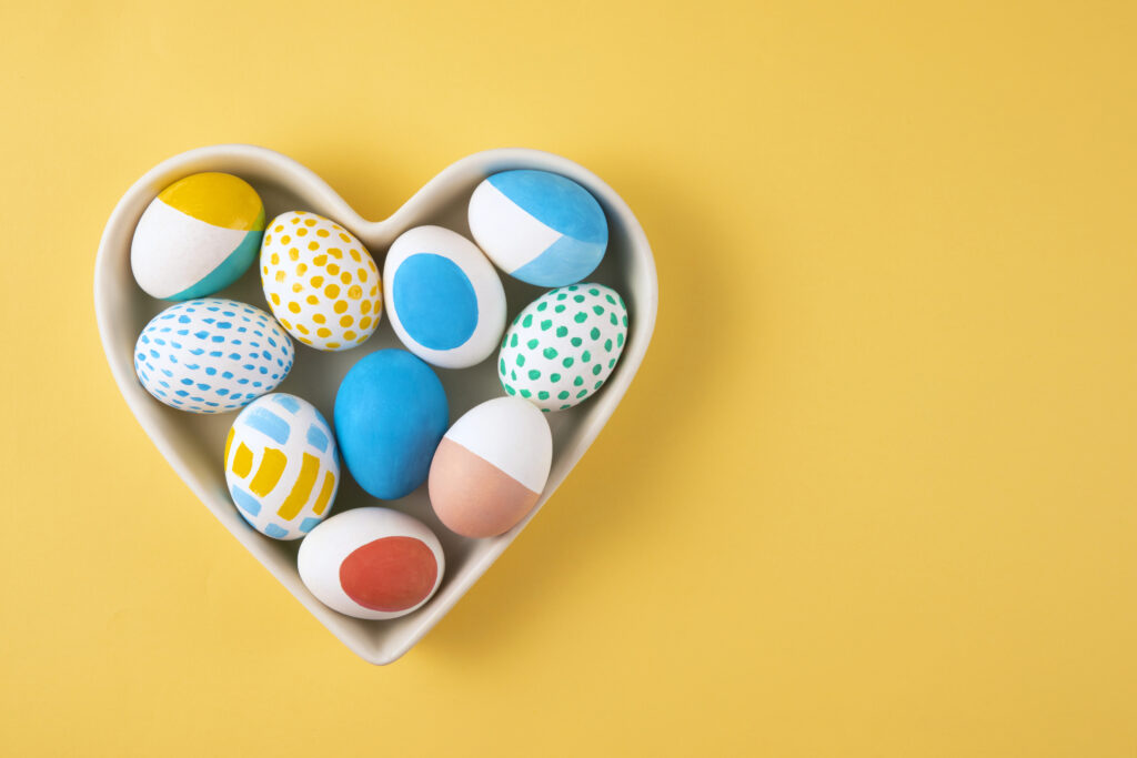 Easter egg treats set in a heart shaped bowl on a yellow background