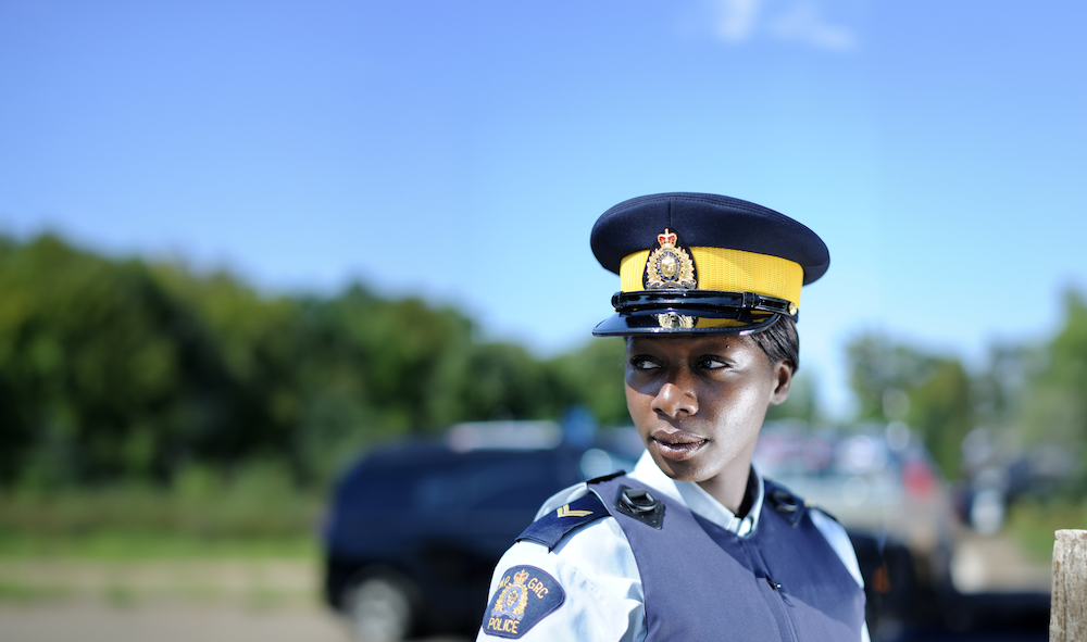 An RCMP officer standing outdoors in front of her vehicle